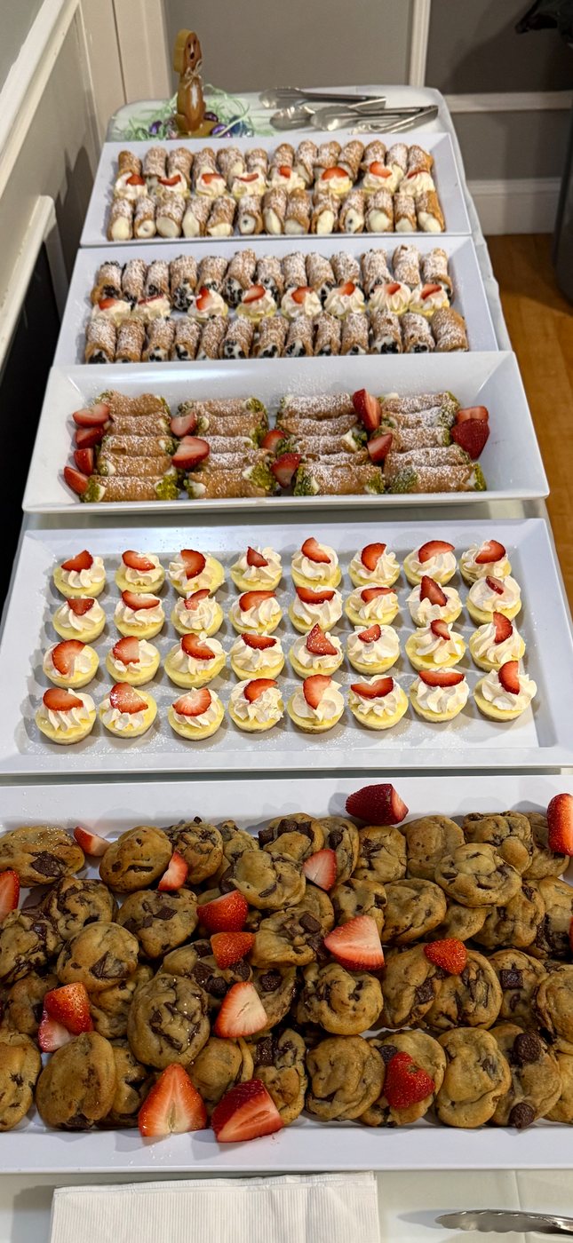 Dessert table with cannoli, mini cheesecakes and chocolate chip cookies