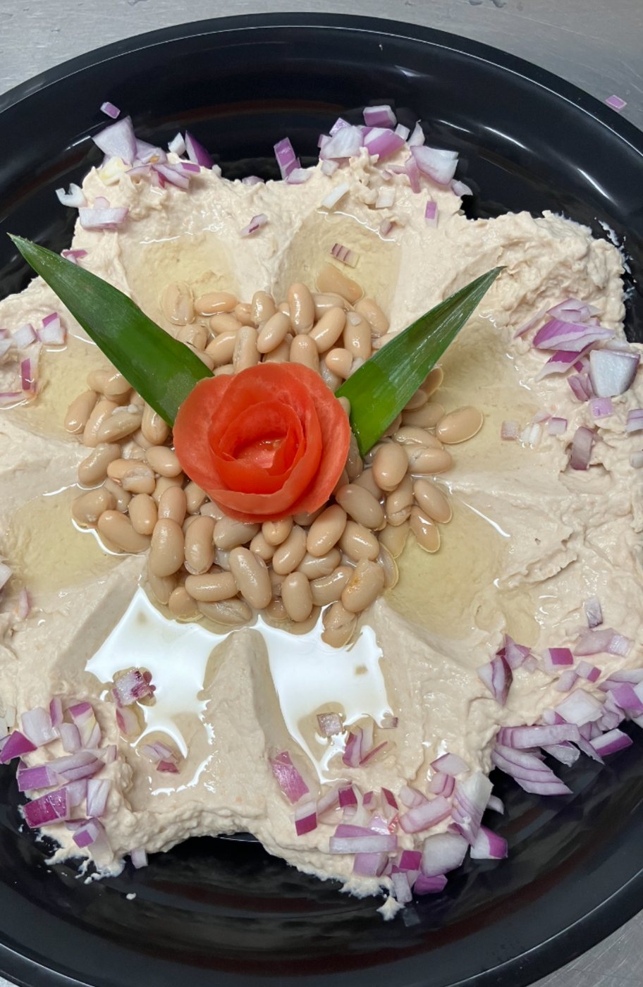 White bean dip garnished with a tomato rose and red onion