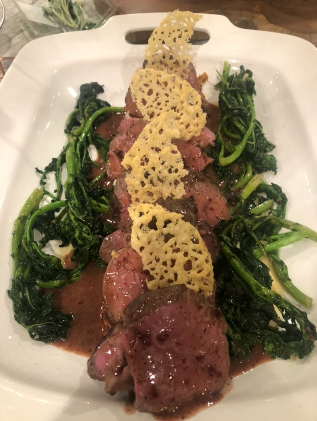 Sliced beef tenderloin over broccoli rabe with parmesan crisps